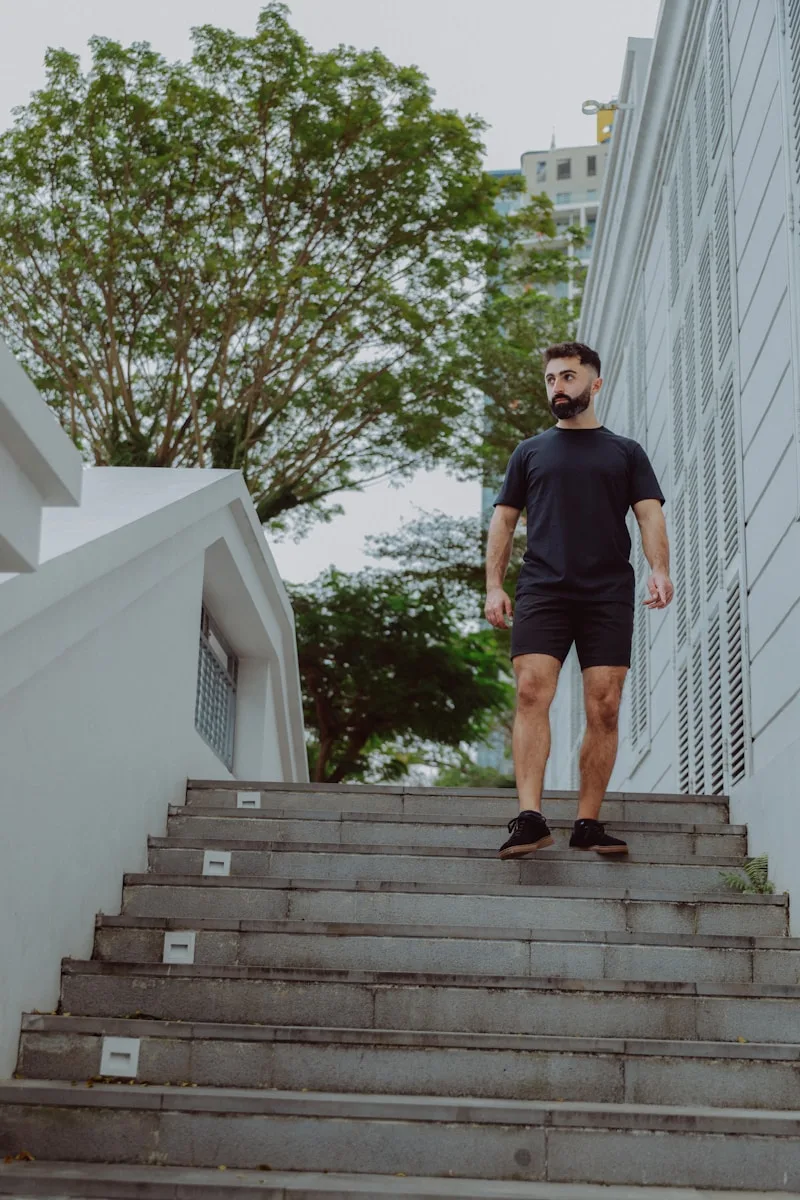 man in black and white t-shirt and black shorts sitting on green grass field during
